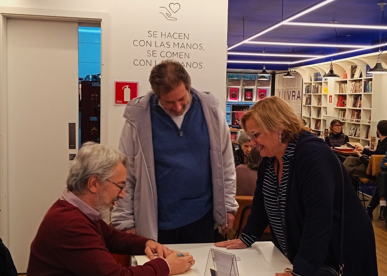 Autor recebendo leitores na mesa de autógrafos