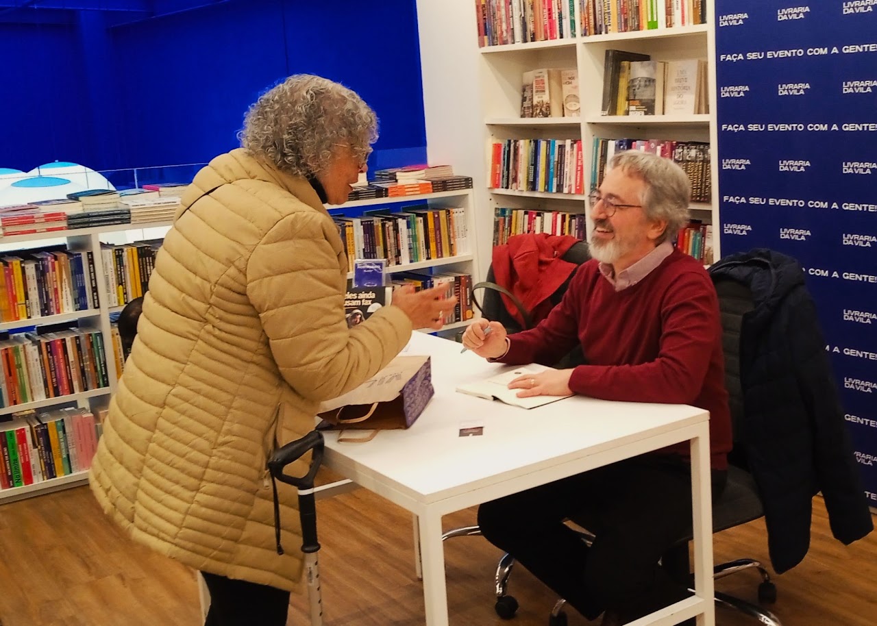 Autor autografando exemplar de “Eles ainda usam fax” para leitora